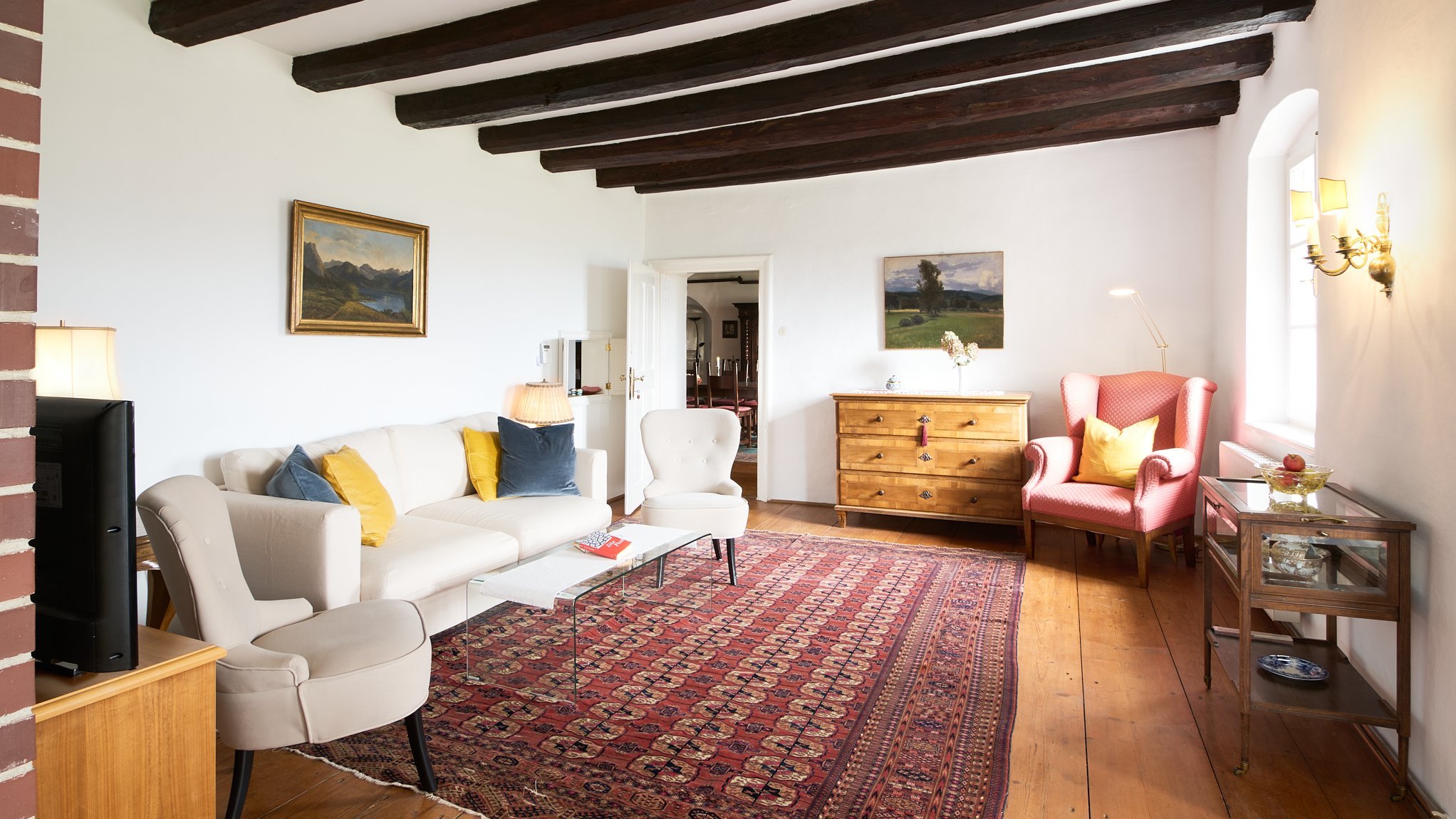 Gemütlicher Wohnraum mit stilvollem Design Ein einladendes Wohnzimmer mit Sofa, Sesseln und Holzmöbeln sowie Kunstwerken an der Wand.