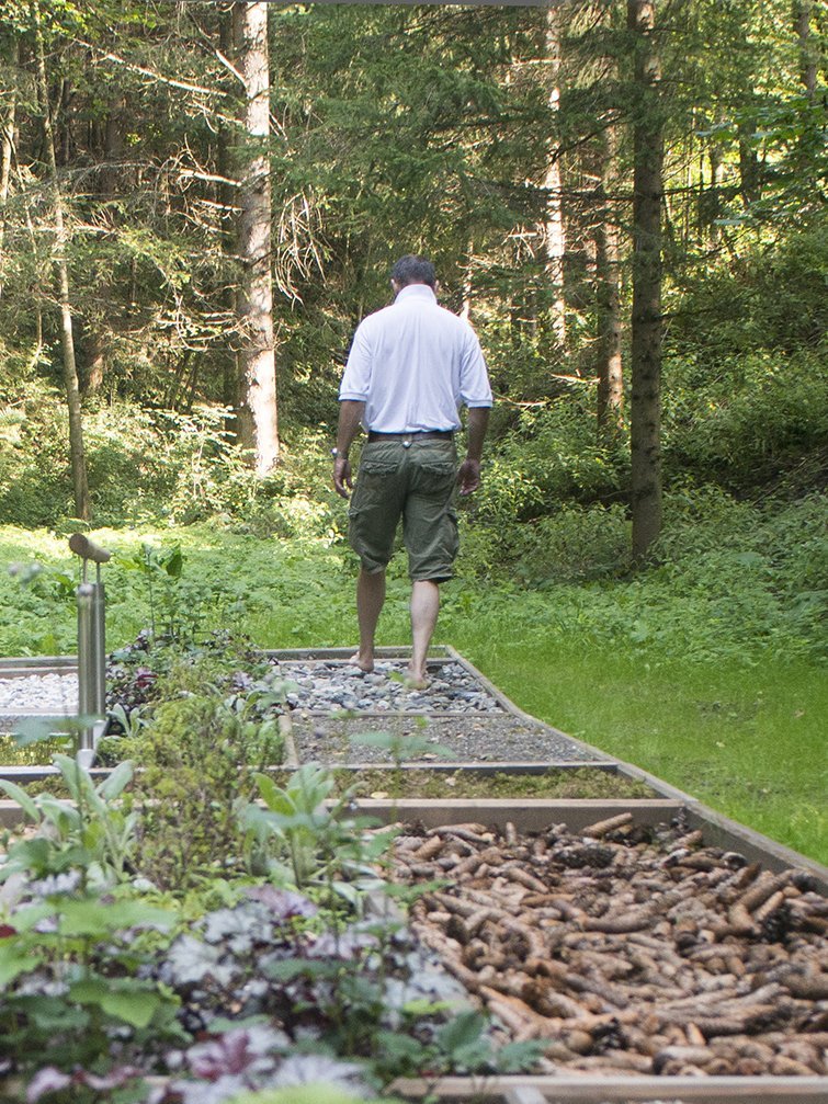 Wohlfühlweg im Wald Person geht auf einem Wellnesspfad durch den Wald, umgeben von Naturmaterialien und Pflanzen
