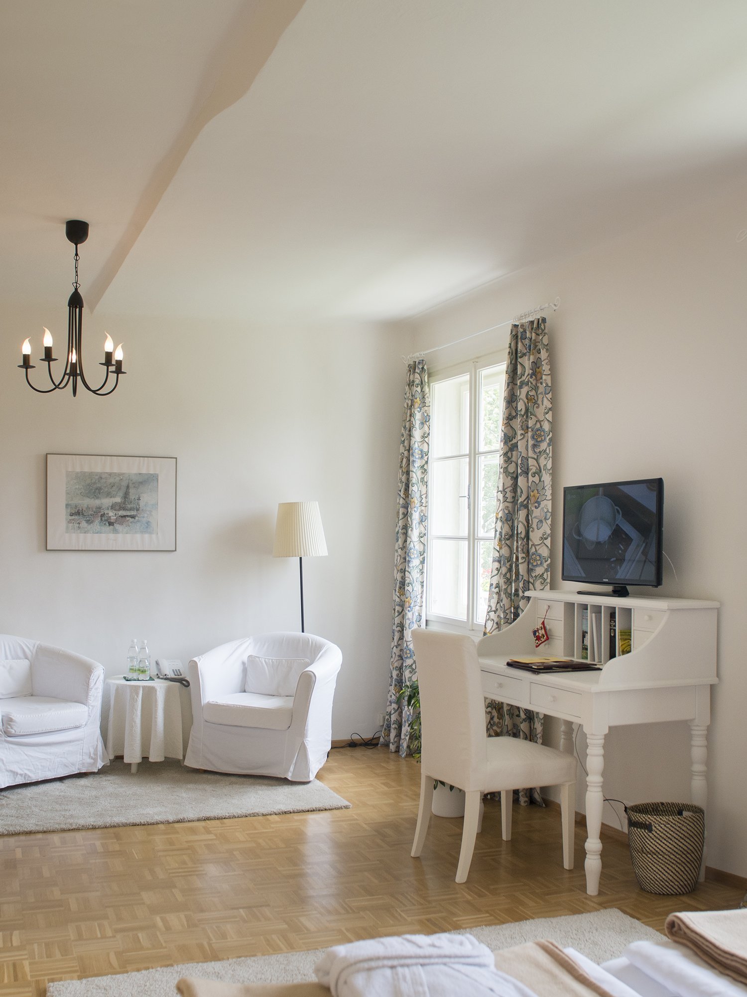 Helle Wohnatmosphäre mit modernem Design Lichtdurchflutetes Wohnzimmer mit weißen Stühlen, Tisch und Schreibtisch vor großen Fenstern