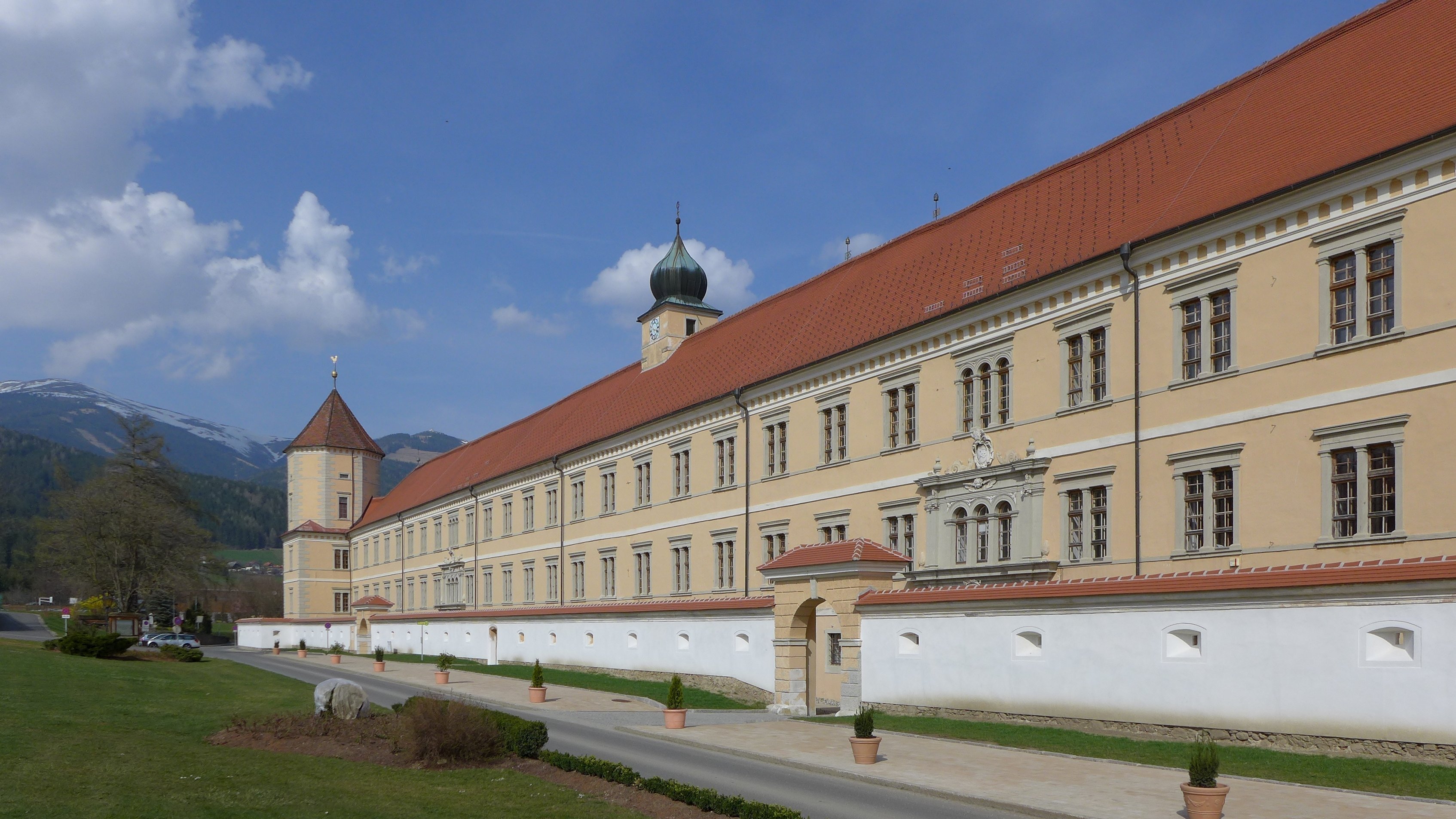 Historische Abtei Seckau in Berglandschaft Großes historisches Klostergebäude vor einer bergigen Kulisse unter blauem Himmel
