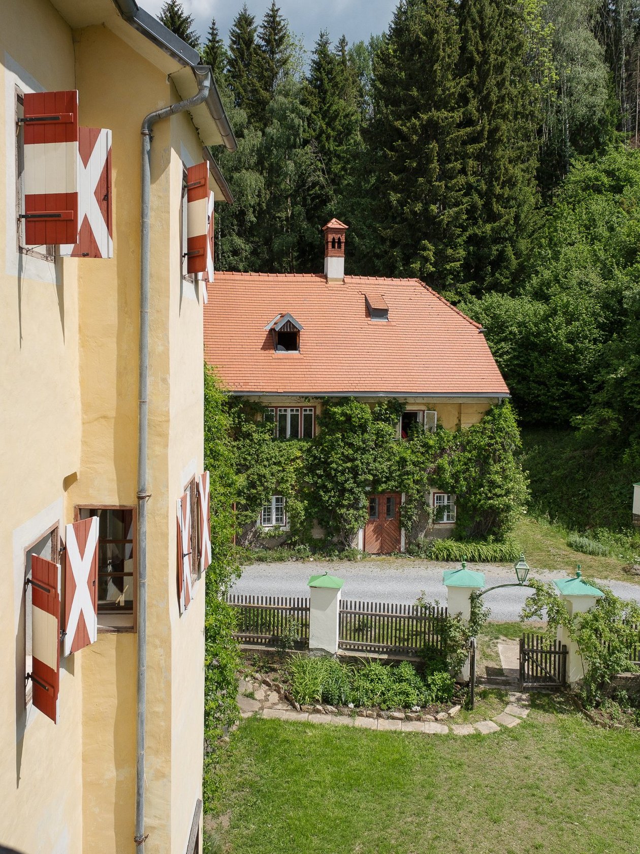 Hotel Landsitz Pichlschloss Das Hotel Landsitz Pichlschloss mit roten und weißen Fensterläden, umgeben von Grünanlagen und einem gepflegten Garten