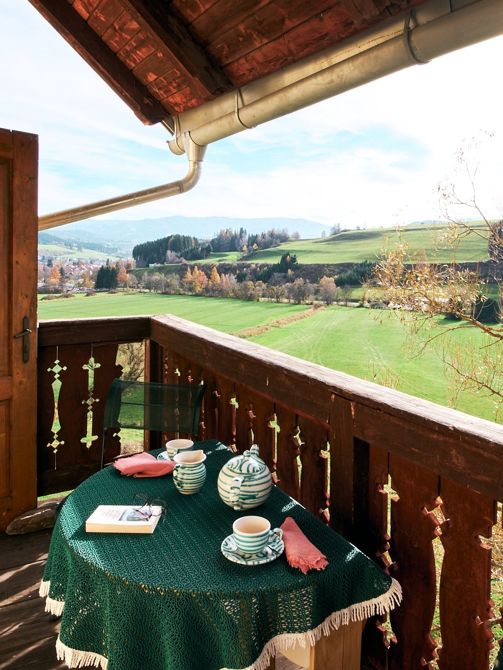 Balkon mit Tisch für das Essen im Freien und Blick auf eine grüne Landschaft in der Steiermark.