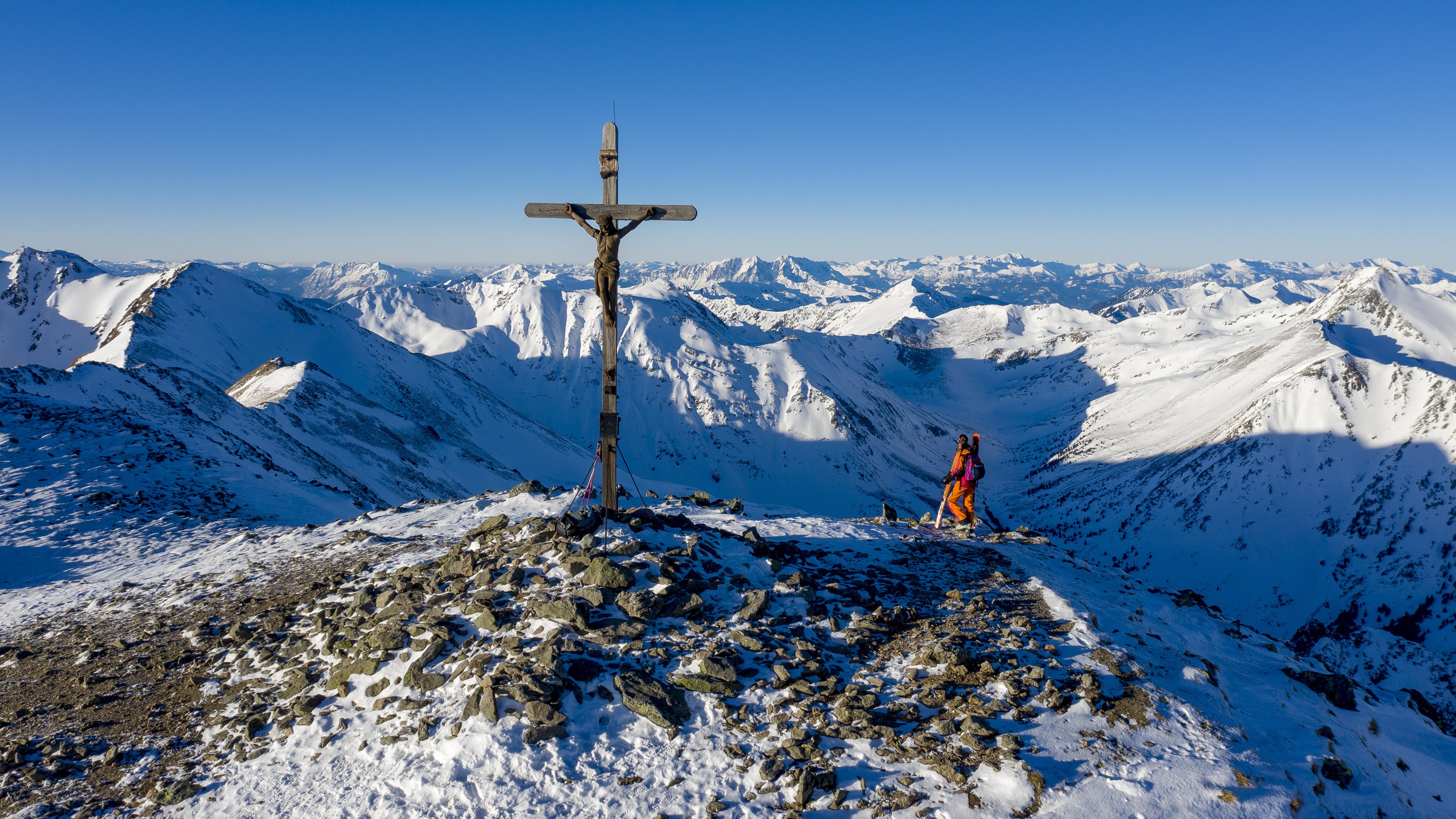 Schneebedeckte Berglandschaft mit Gipfelkreuz Berglandschaft mit schneebedeckten Gipfeln und einem Kreuz auf dem höchsten Punkt