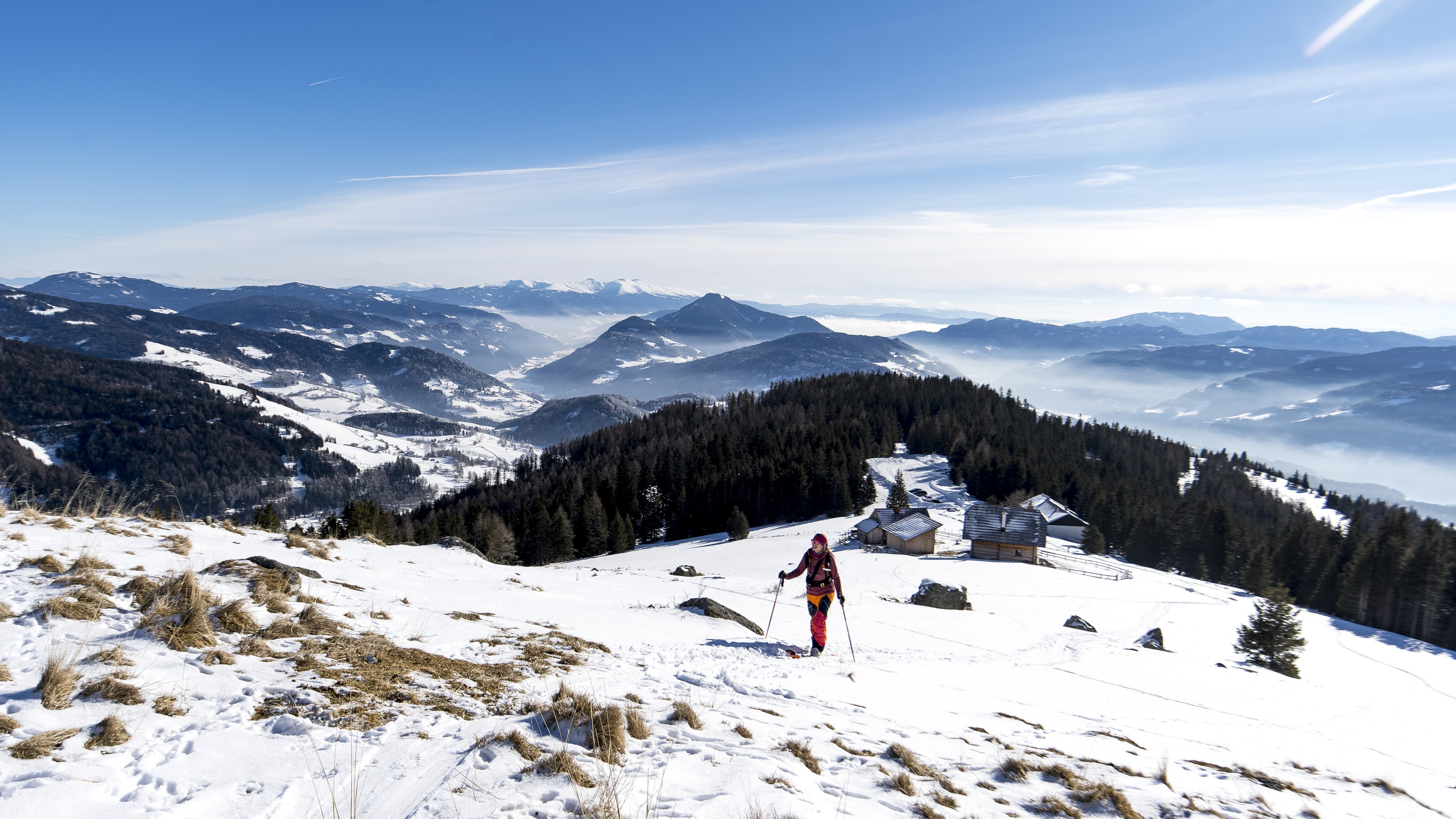 Skifahrer im Schnee bei klarem Himmel mit Bergen im Hintergrund, Skiregion Steiermark