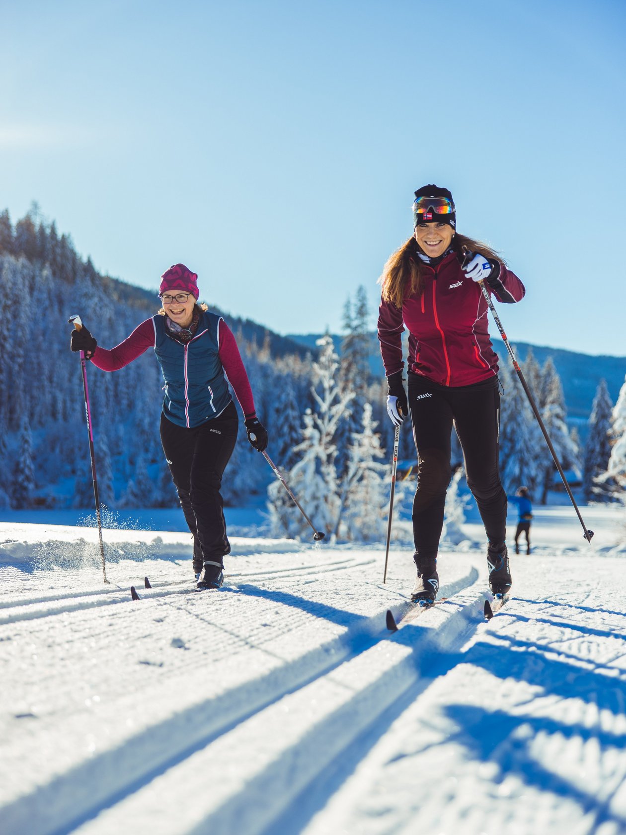Aktive Winterfreude beim Langlaufen Zwei Frauen beim Langlaufen auf einer verschneiten Strecke mit Berglandschaft im Hintergrund