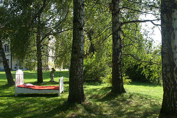Ein altes Holzbett mitten Schlosspark unter den großen Laubbäumen